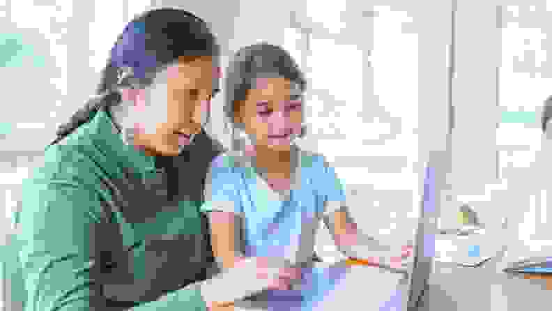 A parent and a child browsing on a laptop.