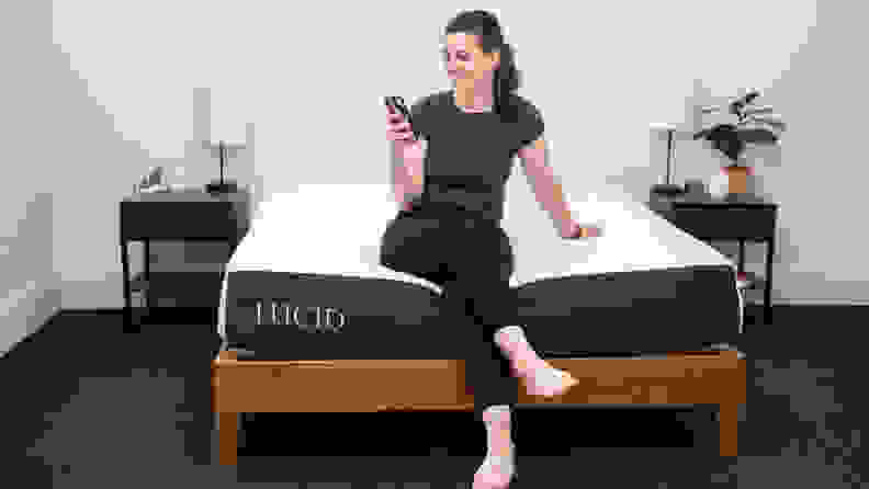 A person sitting on the bottom edge of the Lucid mattress.