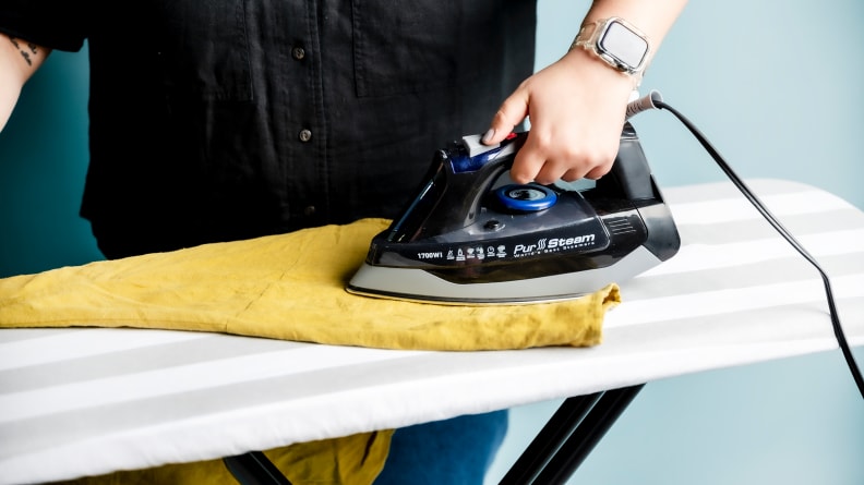 A person using the Pursteam iron on an yellow shirt.