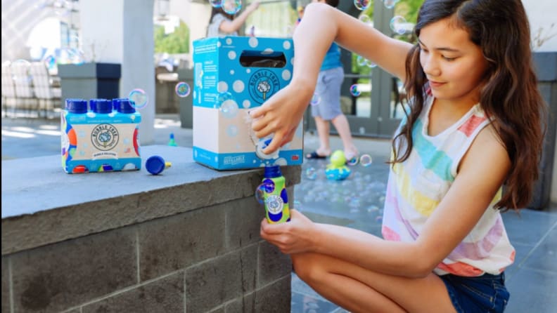 A child refills her bubble solution bottle from a spout