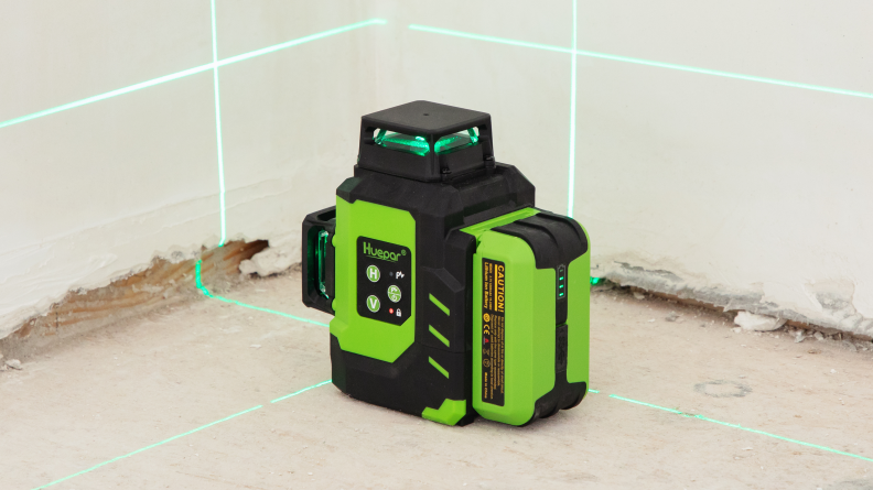 A green laser level shoots a gridded green light onto a wall.