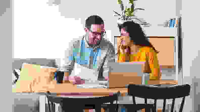 Couple sitting at kitchen table looking at computer screen