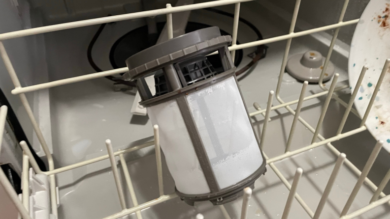 A dishwasher filter propped up in a dishwasher rack.