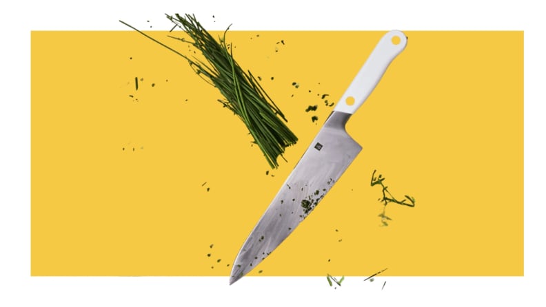 Couteau de chef coupant la ciboulette sur fond jaune