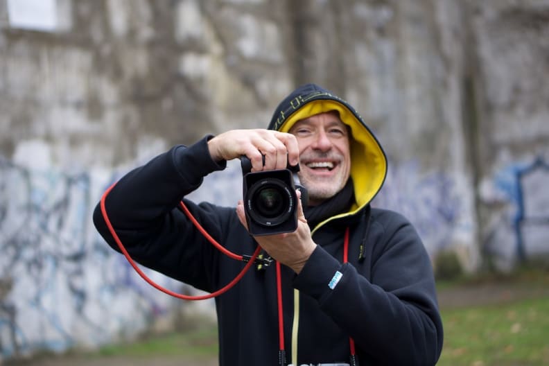 Photographer laughing while shooting with with interchangeable lens camera.