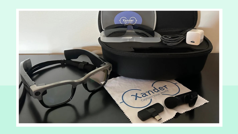A XanderGlasses eyewear kit complete with a pair of glasses, several chargers, a cleaning cloth and a carrying case.