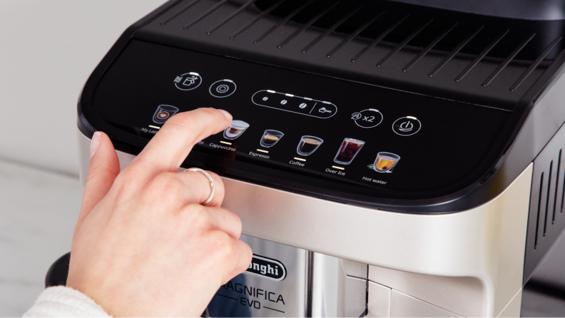 A hand pressing the buttons on the coffee maker.
