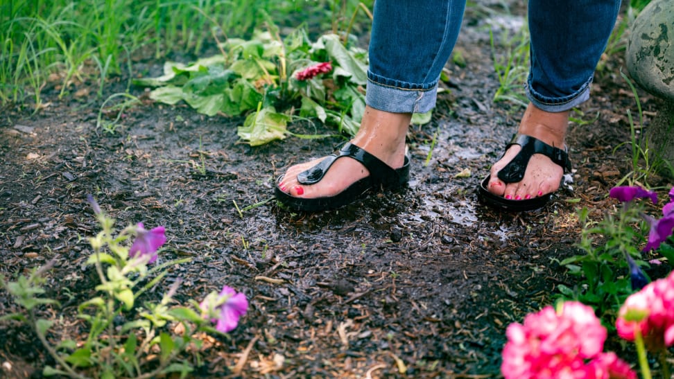 Girl wearing waterproof Birkenstock sandals stands in a garden.