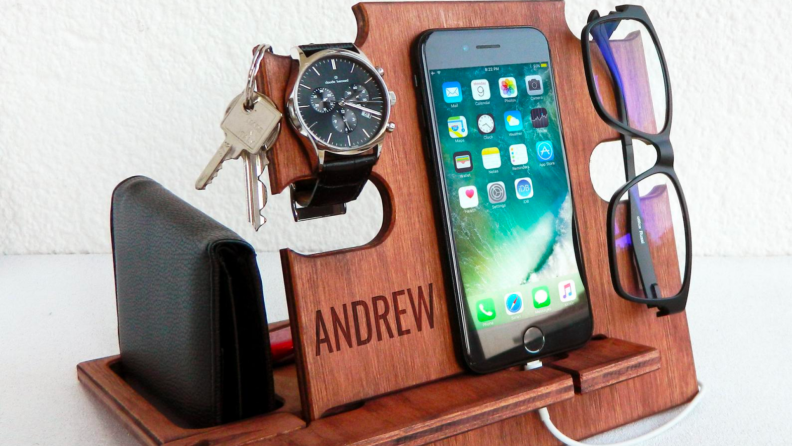 A wooden docking station with a cell phone and keys.