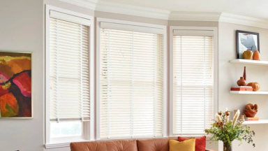 An image of a wall with three large windows, all with slatted white window blinds.