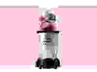 Magic Bullet blender filled with fruit on a pink background
