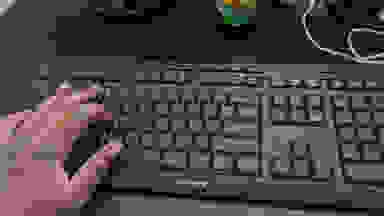 A person's hand touching a black keyboard