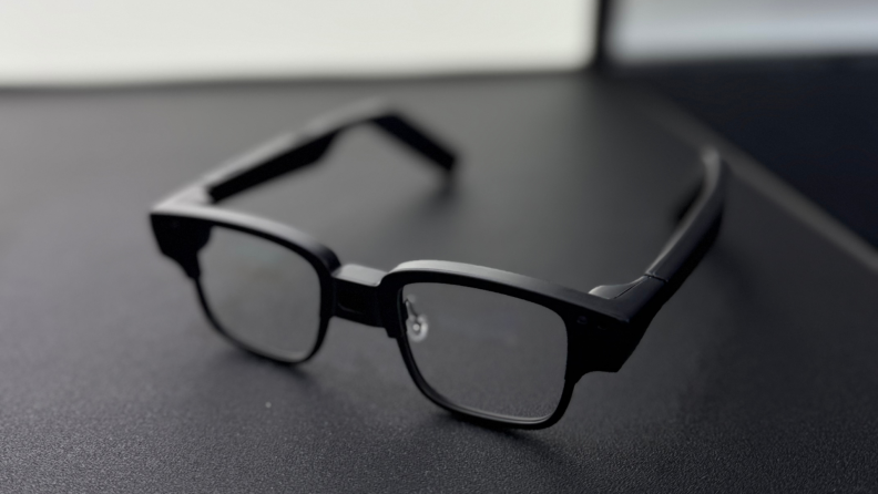 Techno's AI glasses sit on a black table, alone.