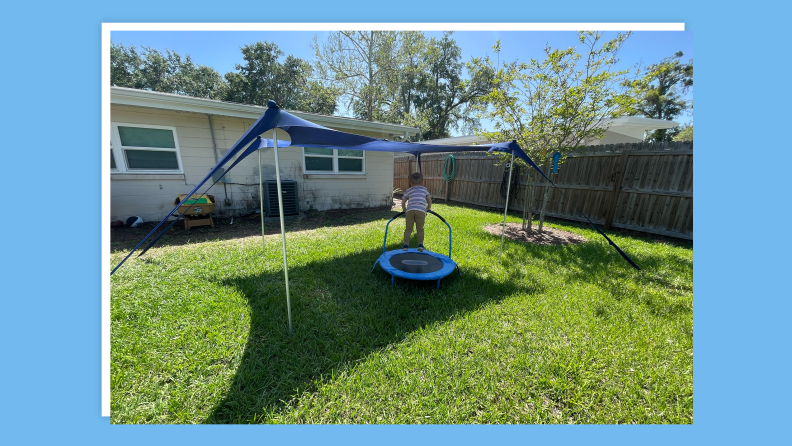 Small child bouncing on small, circle trampoline outdoors.