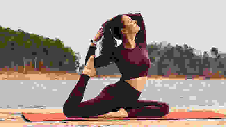 A woman practicing yoga wearing the Fitbit Charge 5.