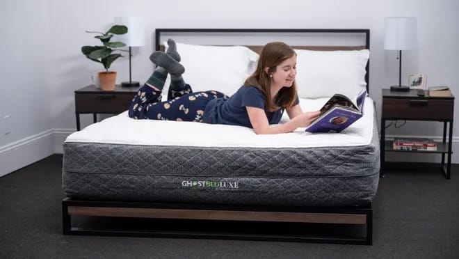 GhostBed mattress with a woman on top of it in a bedroom setup.