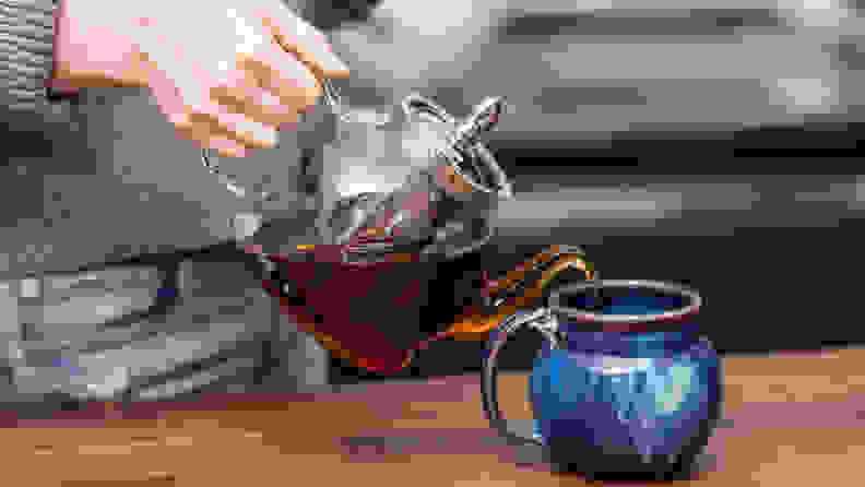 Tea from a the Hiware glass teapot is poured into a blue ceramic mug.