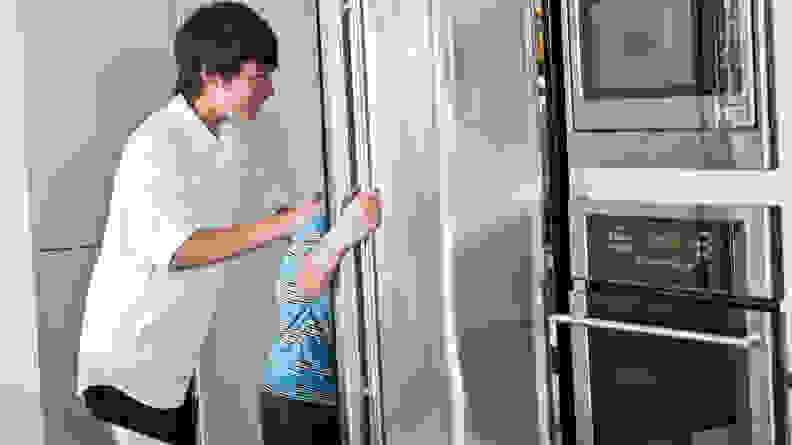 Two playful kids, excitedly rummaging through their refrigerator.