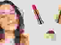 On the left: A person with long brown hair wears a coral lipstick and smiles at the camera. On the right: Three makeup products in gold packaging.