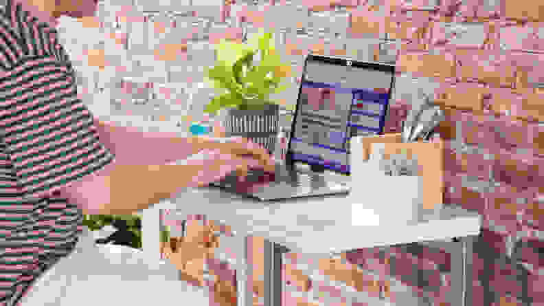 A small desk in workstation mode with a person sitting at the desk and typing on a computer