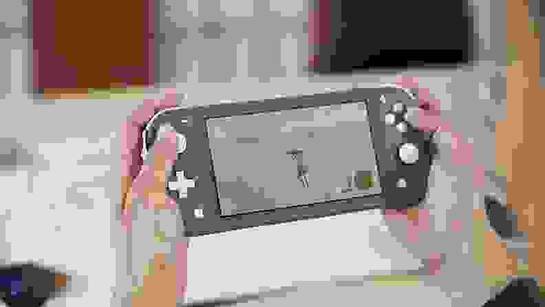 Close up of a person playing a Nintendo Switch Lite