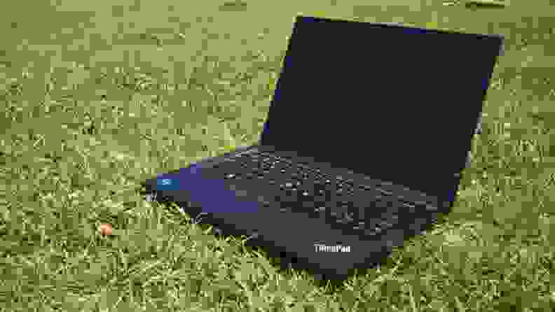 An open laptop resting on a field of grass