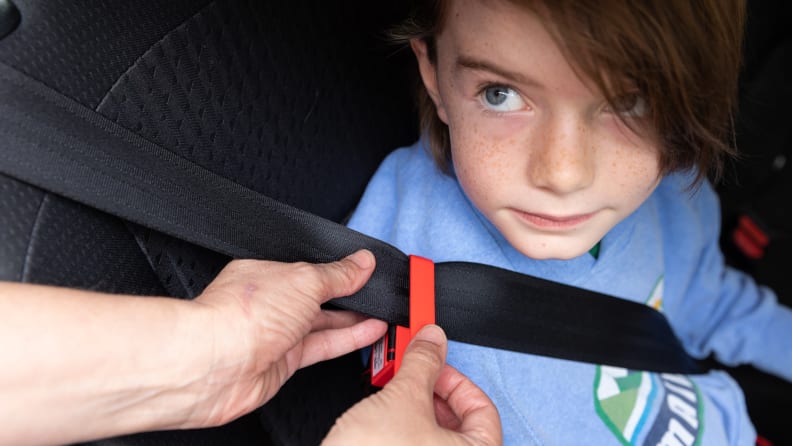A child looks up as his seatbelt is adjusted