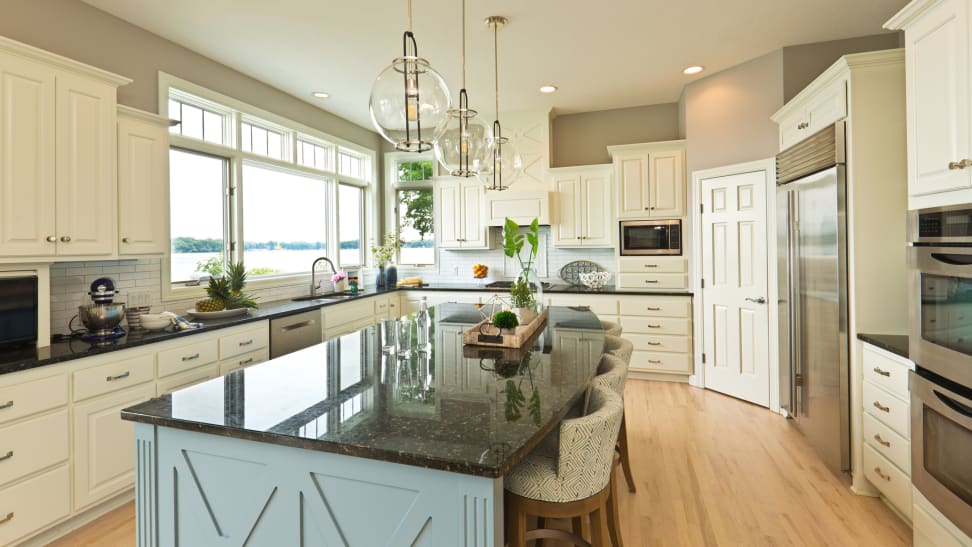 A transitional kitchen with white cabinetry, a blue island, and stainless steel appliances