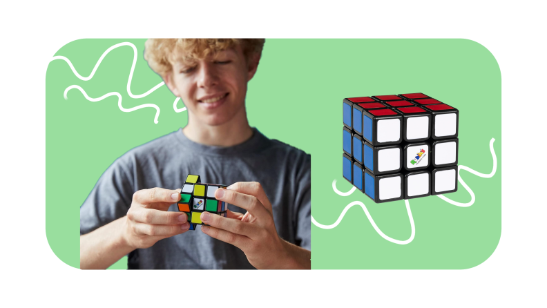 Small child playing with Rubik's Cube puzzle toy next to enlarged Rubik's Cube.