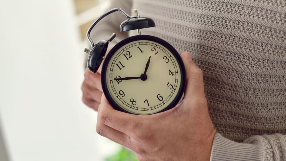 a person holds the clock as they adjust the time