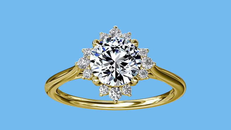 An image of a gold banded engagement ring with nine tiny diamonds haloing a round diamond centerpiece.