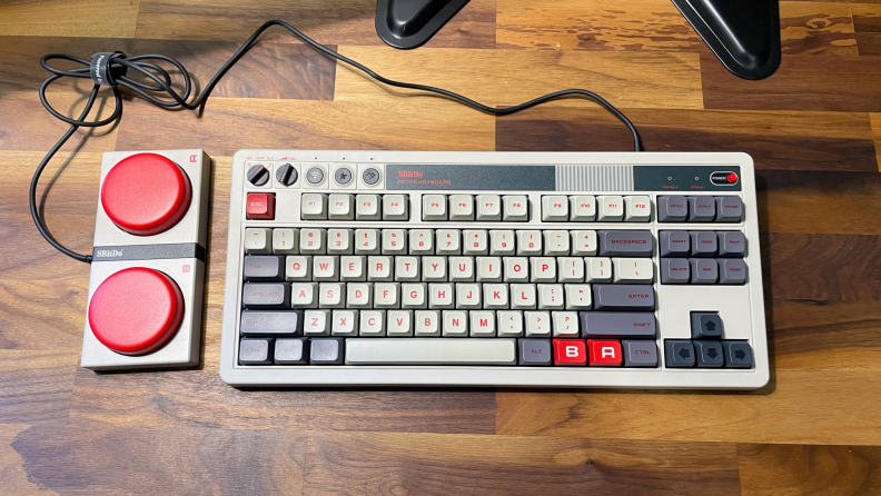 The 8Bitdo Retro Mechanical Keyboard and mouse pad sitting on a wood table.