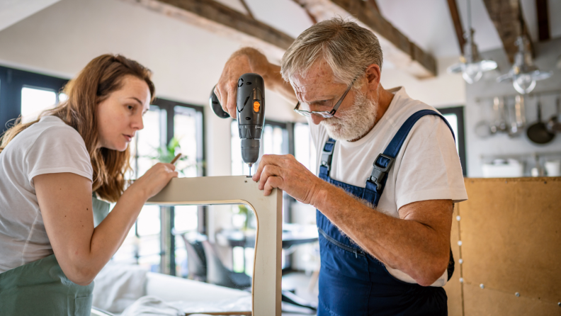 Two people repair furniture inside a home.