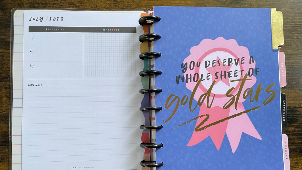 ADHD planner opened to showcase colorful calendar page on top of wooden surface.