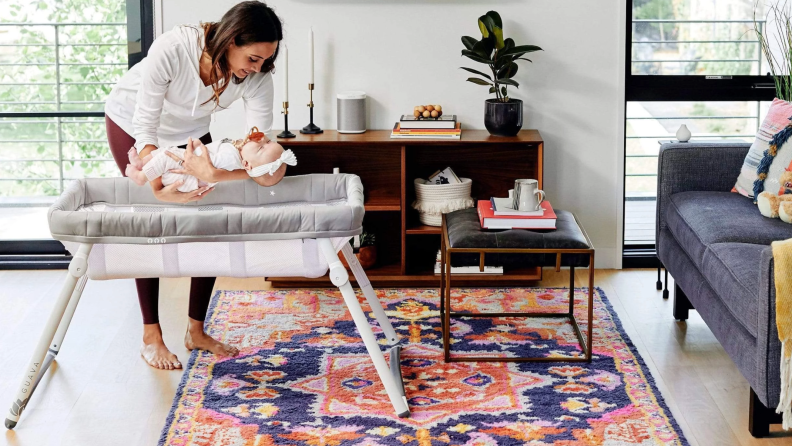 Woman putting baby into Guava Lotus Bassinet