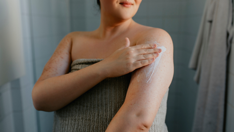 Person rubbing moisturizer on arm after showering.