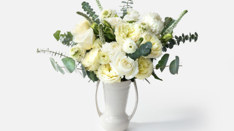 Bouquet of white roses in white vase.