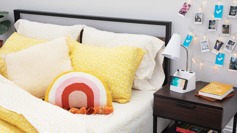 A dorm room with a yellow comforter and throw pillows.