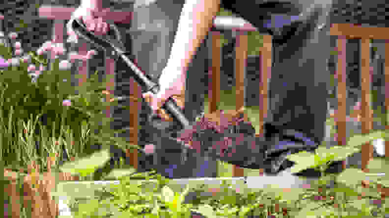 A person digging dirt with the Black & Decker Mini D Handle Shovel