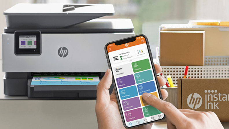 An image of an HP printer fronted by a person holding a smartphone and using the HP Smart app.
