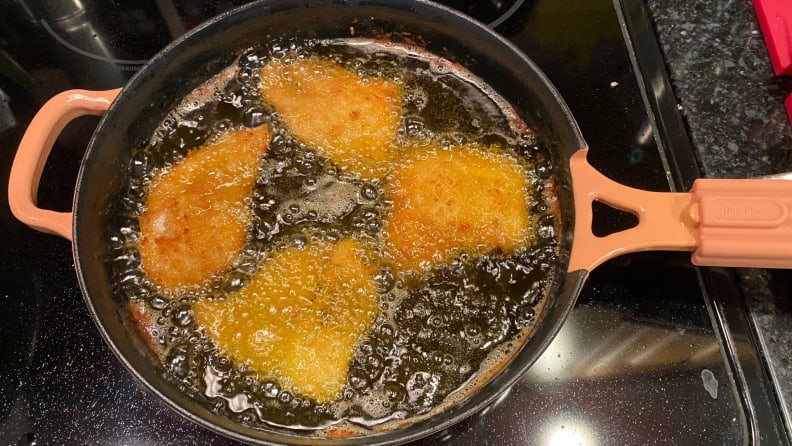 Four chicken breasts fry in oil.
