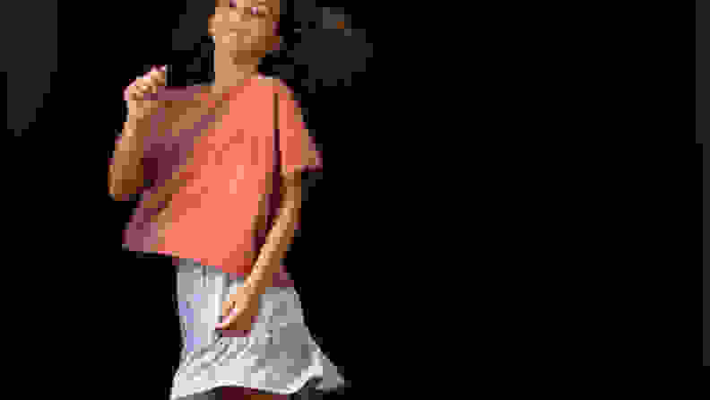A tween, wearing a pink shirt and blue skirt from The Commons, dances on a black background.