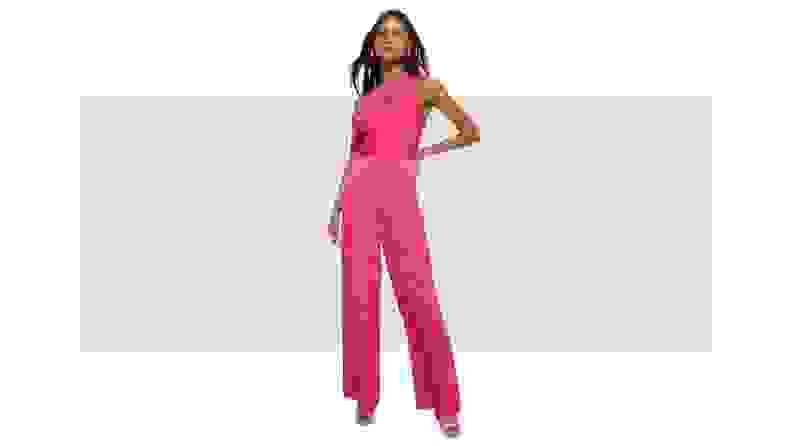 A model wearing a fuchsia satin one-shoulder jumpsuit.