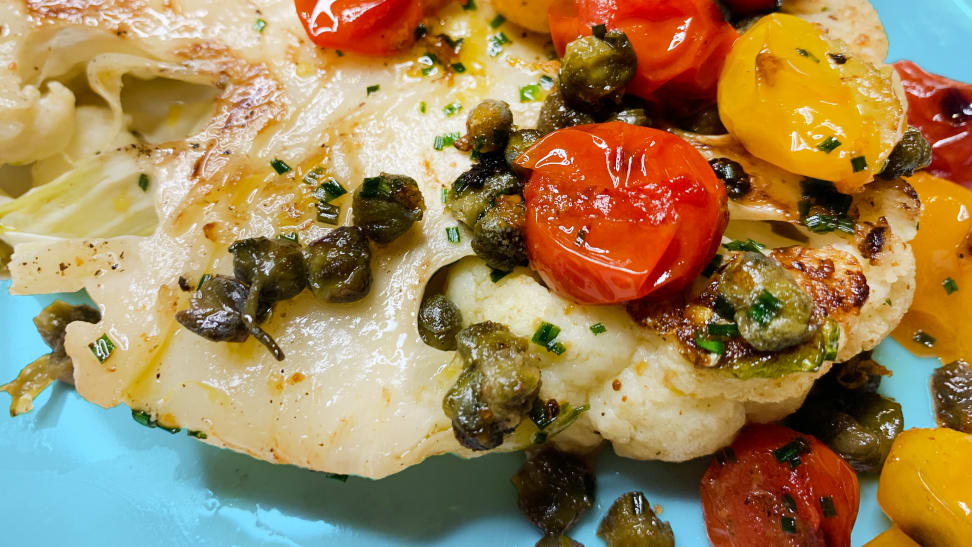A cauliflower steak topped with brown butter, capers, and tomatoes.