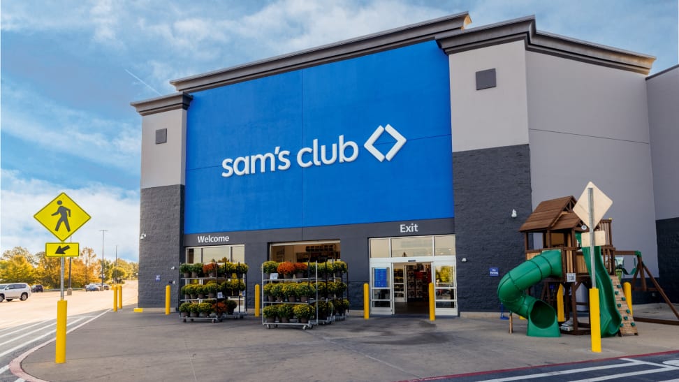 Sam’s Club storefront with blue signage, flower displays, and a wooden playset near the entrance.