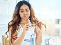 A photo of a woman looking at her hair.