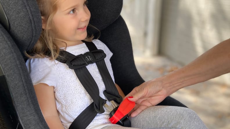 child in carseat that is being buckled in