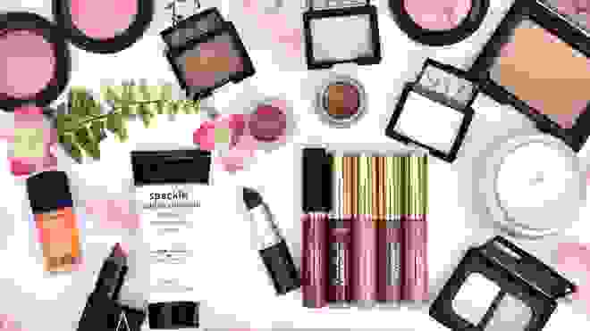 Assorted beauty products next to candle and flowers.