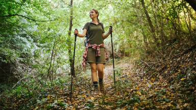 女孩拄着拐杖在树林里徒步旅行。