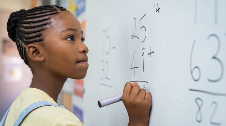 Student at whiteboard doing math problems